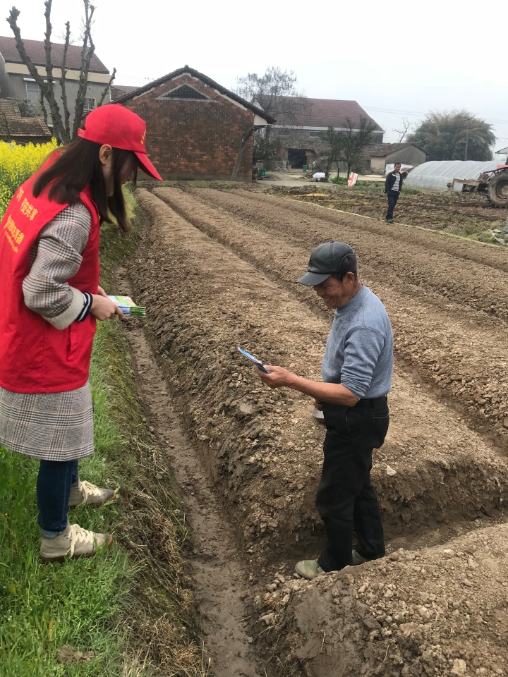 图片四 志愿者在田间向群众发放扫黑除恶知识读本.jpg
